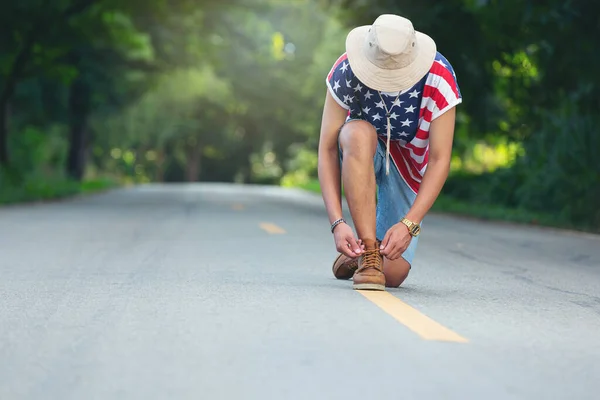 a travelers tie his shoes on country road.