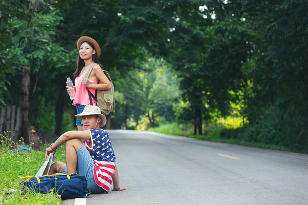 two travelers sitting on country side street