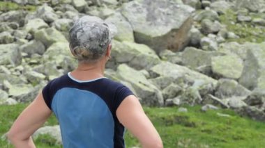 Doğadaki maceralar, dağ yürüyüşündeki genç bir kadın manzaraya hayran kalır ve kameramana bakar.
