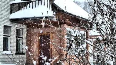 Arka plan videosu. Ahşap pencereli, kırmızı tuğlalı evi olan bir evin arka planında kar yağışı var. Soyut. Noel.