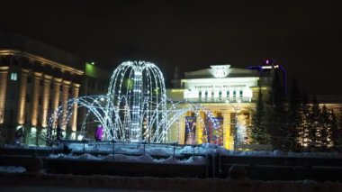 İyi geceler, kış şehri. Aydınlatma, belediye binalarının yakınında parlayan bir çeşme gibi stilize edilmiş. Novosibirsk şehri. Sibirya.