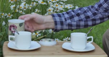 Tea,Vegan.  A man's hand pours tea from a tea bag into the cups on a table in the garden.
