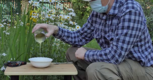 Vegan Καραντίνα Ένας Άντρας Ιατρική Μάσκα Στον Κήπο Χύνει Συμπυκνωμένο — Αρχείο Βίντεο
