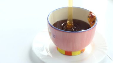 Vejetaryen, çiğ yemek, basit yemek. Bal, beyaz bir tabakta duran bir bardağa damlıyor. Kapat..