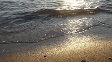 Kumsal. Sörf. Kumsalda dalgalar kopuyor. Rüya, suya yansıyor. Yavaş çekim.