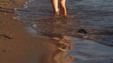 Sörf yaparken sahilde bir kızın ayakları. Ağır çekim. Kapat..
