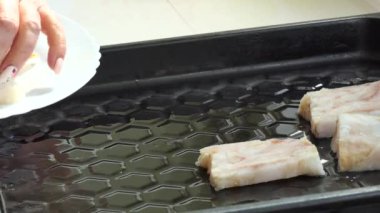 Basit yemek, Asya mutfağından balık yemeği. Aşçı beyaz bir tabaktan balık parçalarını eliyle alır ve pişirmeden önce onları bir pişirme tepsisine koyar. Kapat..