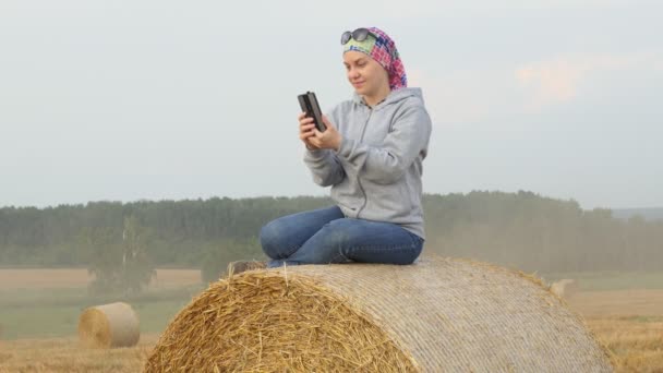 Een Vrouw Kijkt Naar Haar Telefoon Terwijl Een Strobaal Een — Stockvideo