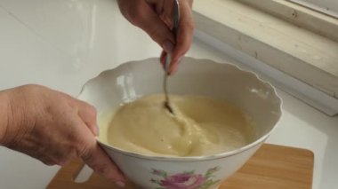 Vejetaryenlik, basit yiyecekler. Aşçı kek hamurunu fincanda karıştırır. Yakın çekim..
