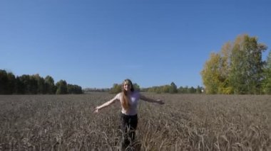 Kadın, sonbahar. Genç, mutlu bir kadın buğday tarlasında koşuyor..