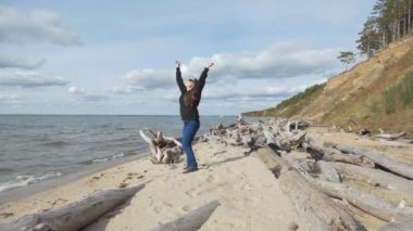 Çevre. Genç bir kadın akıntı tarafından ağaç gövdelerinin getirildiği nehir kıyısında yürüyor. Ob Nehri, Sibirya. Yavaş çekim.