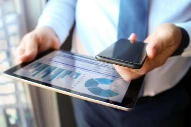 Bir tablet ve cep telefonu grafikler üzerinde çalışma ve mali analiz iş adamı rakamlar