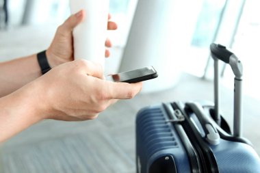 Havaalanında bekleyen yolcular / mobil telefon ve içecek kahve veya tee kullanarak yolcu