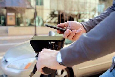 Elektrikli scooterlı bir adamın cep telefonuyla ödeme yaptığı görüntüyü kapat