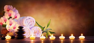 Spa Konsept - masaj taşlarla havlu ve mumlar doğal arka planda