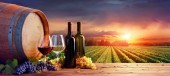 Flaschen und Weingläser mit Trauben und Fass in der ländlichen Szene