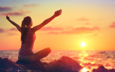 Gevşeme ve Yoga gün batımında - kız okyanus seyir kollarını açarak