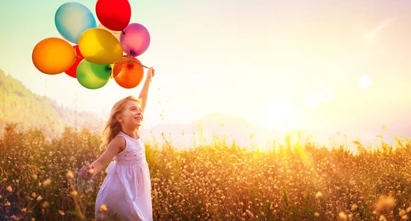 快乐的孩子在日落时与气球在田野里奔跑 — 图库照片