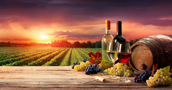 Barrel Wineglasses And Bottle In Vineyard At Sunset