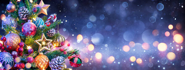 Рождественская елка - украшения, висящие на сосене с разряженным светом в блестящей ночи