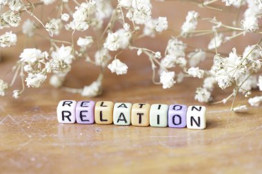 Seçici odak. Kahverengi arka plan üzerinde bebek nefes çiçek ile renkli alfabe kare boncuk Kelime İlişki kombinasyonu