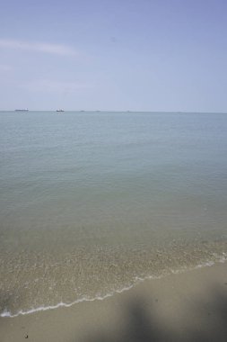 Parlak yansıyan, güneşli, kumlu sahil arka planı.