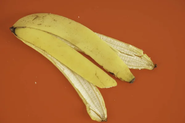 赤い背景にバナナの皮 — ストック写真