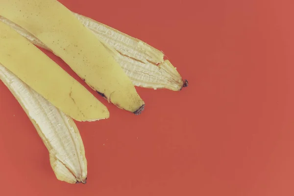 赤い背景の上に黄色のバナナの皮 — ストック写真