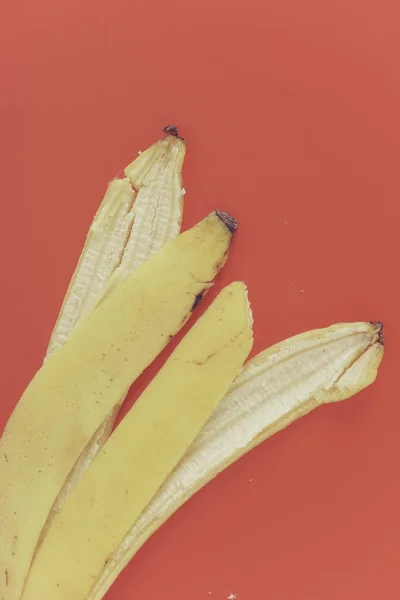 赤い背景の上に黄色のバナナの皮 — ストック写真