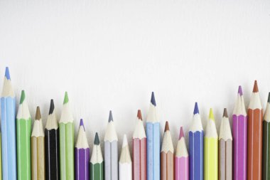 Beyaz kağıt üzerinde gökkuşağı renkli kalemler 