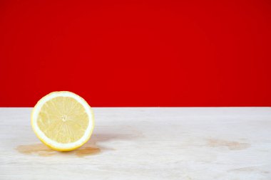 beyaz masa yüzeyi ve kırmızı duvar arka plan üzerinde sarı limon bir yarısı 