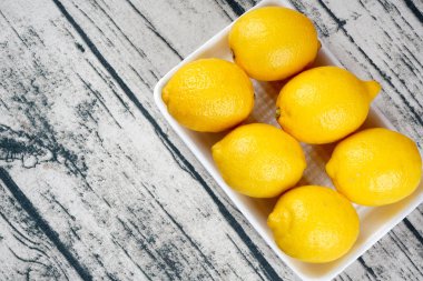 tabakta bütün sarı limon, açık ahşap masa yüzeyi 