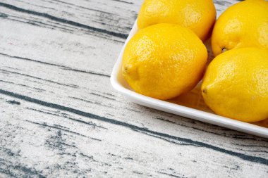 tabakta bütün sarı limon, açık ahşap masa yüzeyi 