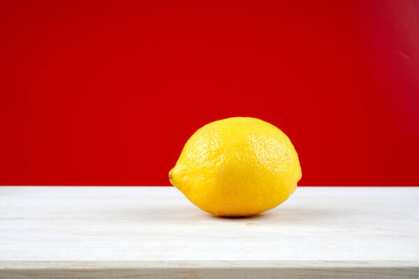 один желтый лимон на белой поверхности стола
 