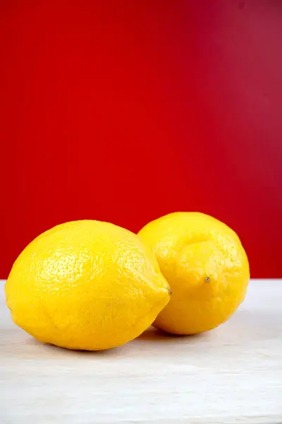 Dos Limones Amarillos Enteros Superficie Ligera Mesa Madera Fondo Rojo — Foto de Stock