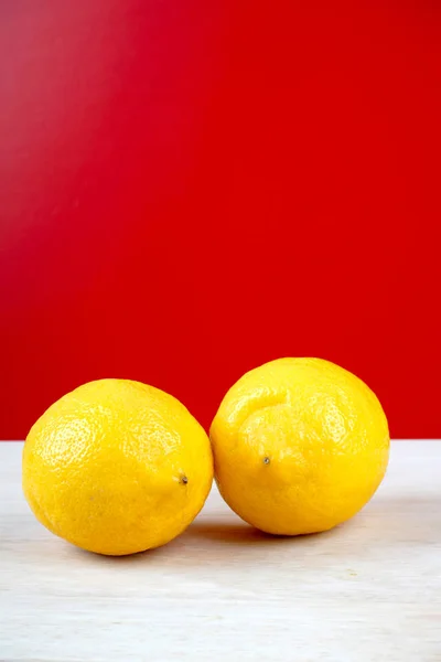 Dos Limones Amarillos Enteros Superficie Ligera Mesa Madera Fondo Rojo — Foto de Stock