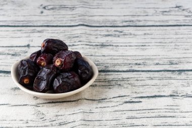 kase plaka, gri ahşap masa yüzeyinde kuru koyu mavi tarihler meyve 