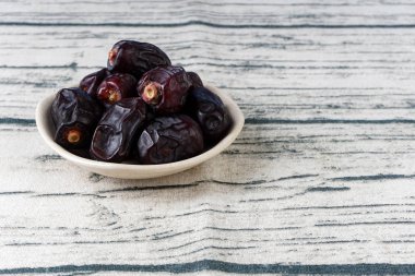 kase plaka, gri ahşap masa yüzeyinde kuru koyu mavi tarihler meyve 
