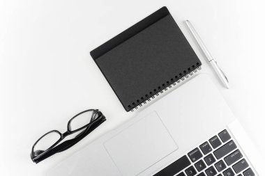 dizüstü bilgisayar ile beyaz yüzeyüzerinde gözlük, kağıt ders kitabı ve kalem ile işyeri masa 