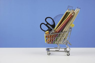 okul malzemeleri, renkli kalemler ile tekerlekler üzerinde küçük metal alışveriş sepeti