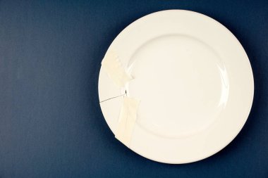 mavi yüzeyüzerinde bir beyaz porselen kırık plaka 