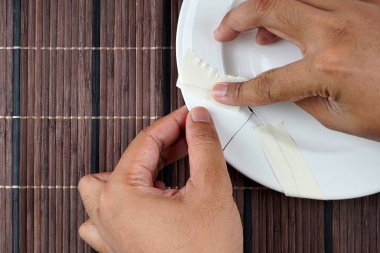 beyaz porselen kırık plaka, plaka düzeltmek için çalışan kişi 