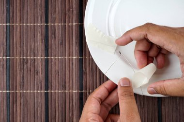 beyaz porselen kırık plaka, plaka düzeltmek için çalışan kişi 