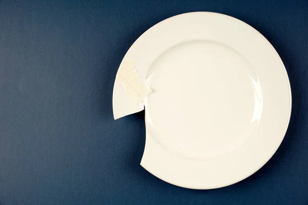 one white porcelain broken plate on blue surface
