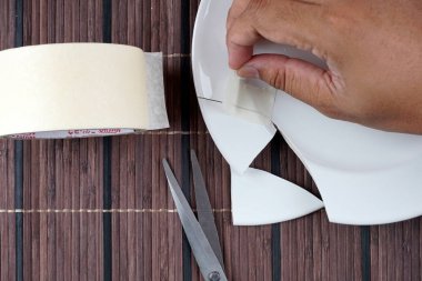beyaz porselen kırık plaka, plaka düzeltmek için çalışan kişi 