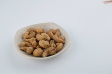 Kızarmış kaju fıstığı tabakta beyaz masanın üstünde..