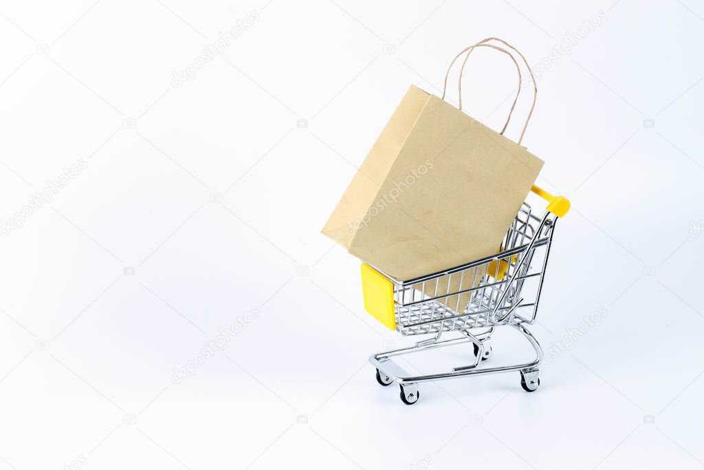 carton shopping paper bag isolated on white and small metal shopping cart on wheels 