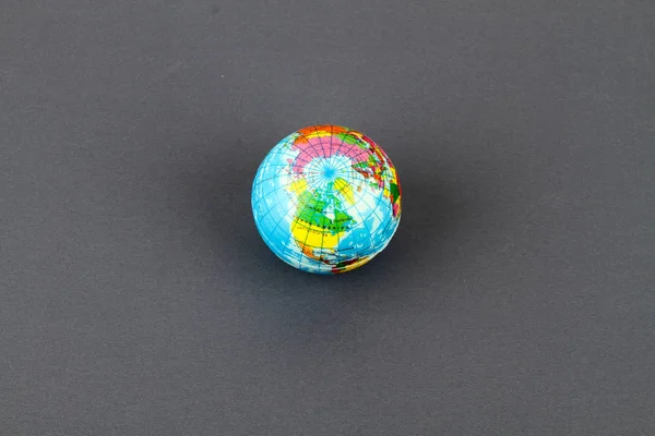 studio shot of small earth planet globe toy isolated on grey