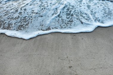 bej kumlu plaj ve köpük ile mavi su dalgaları 