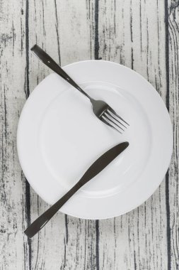 gümüş, paslanmaz çatal ve beyaz plaka ile ahşap masa üzerinde bıçak 